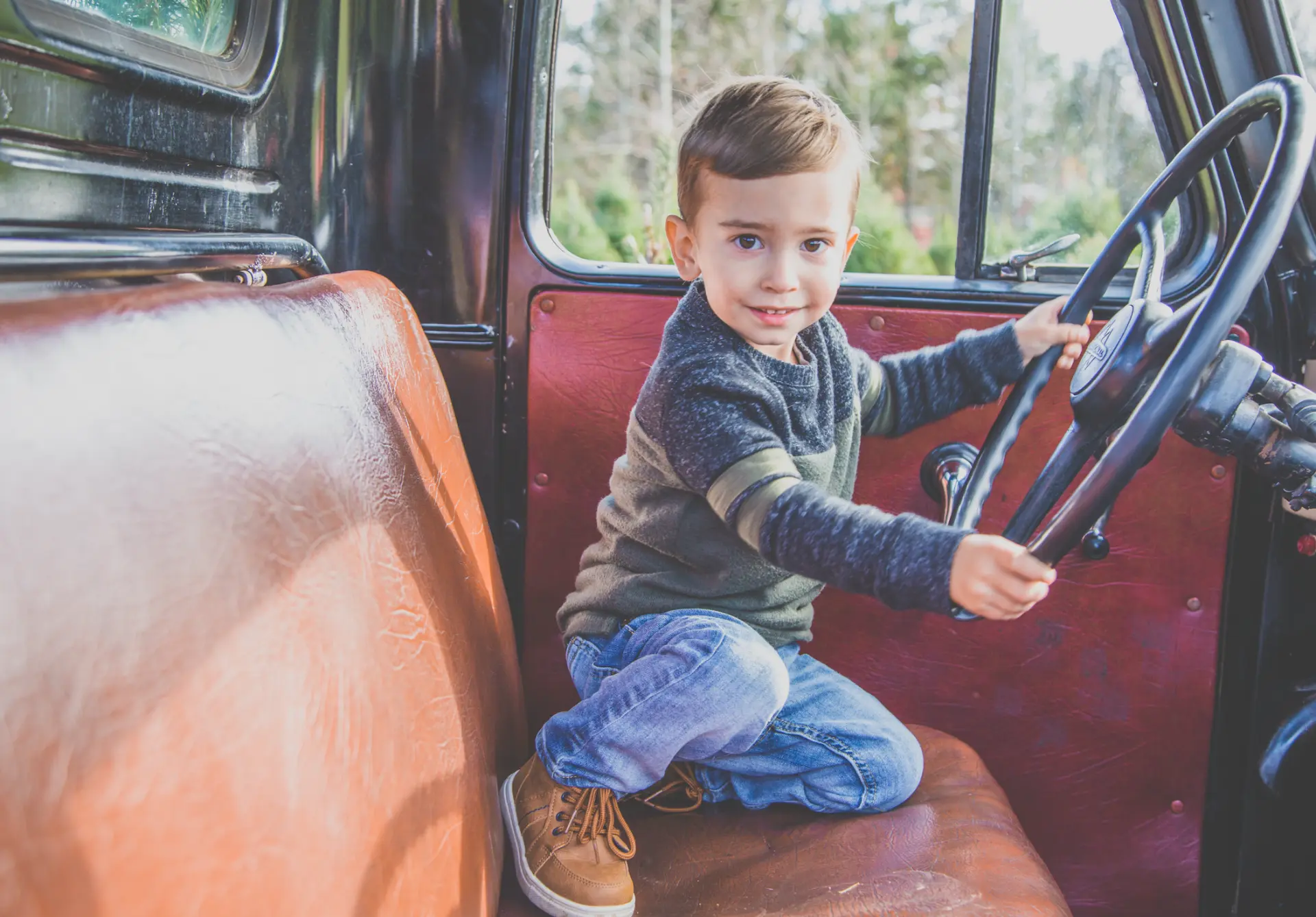 Toddler boy at the wheel of a vintage pickup truck