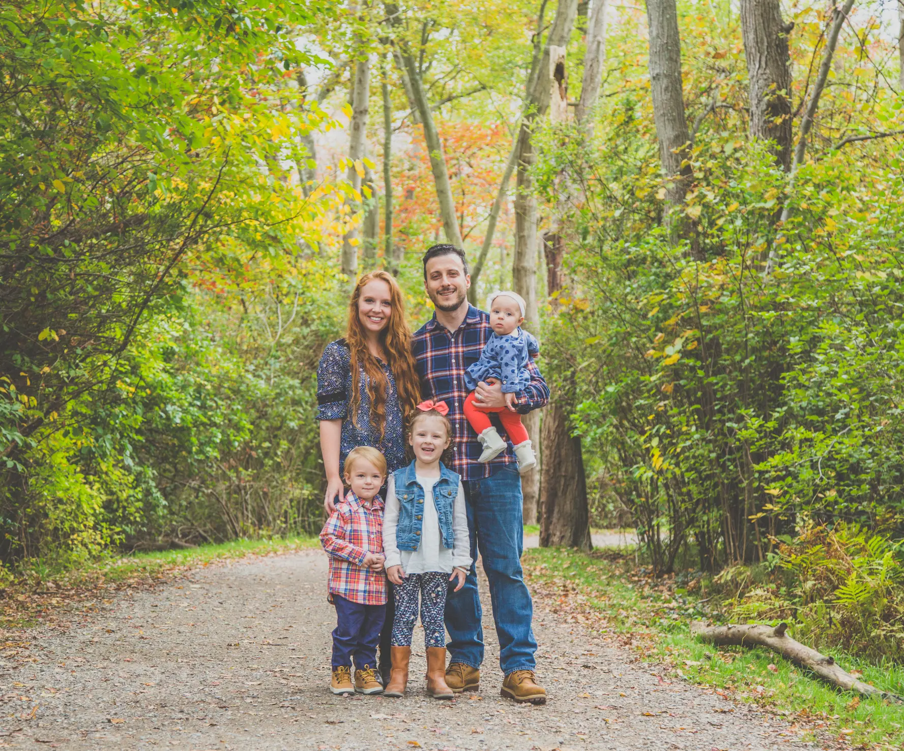 Family of five with three young kids on an autumn woodland trail